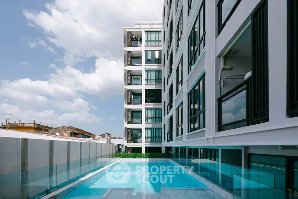 Modern apartment building with a luxurious pool and stunning architectural design.