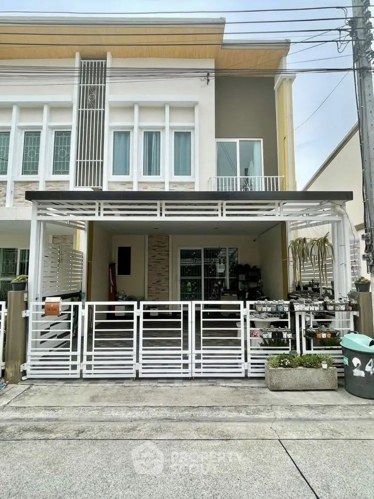 Modern townhouse exterior with gated entrance and small garden area.