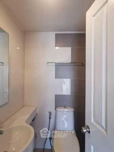 Modern bathroom with sleek design and neutral tones, featuring a toilet and sink.