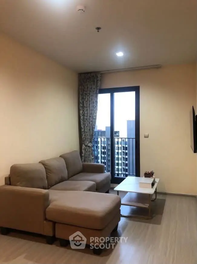 Cozy living room with modern sofa and city view balcony in high-rise apartment.