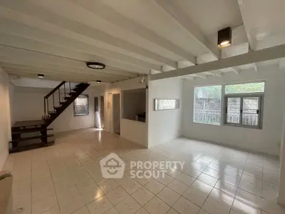 Spacious open-plan living area with modern staircase and large windows