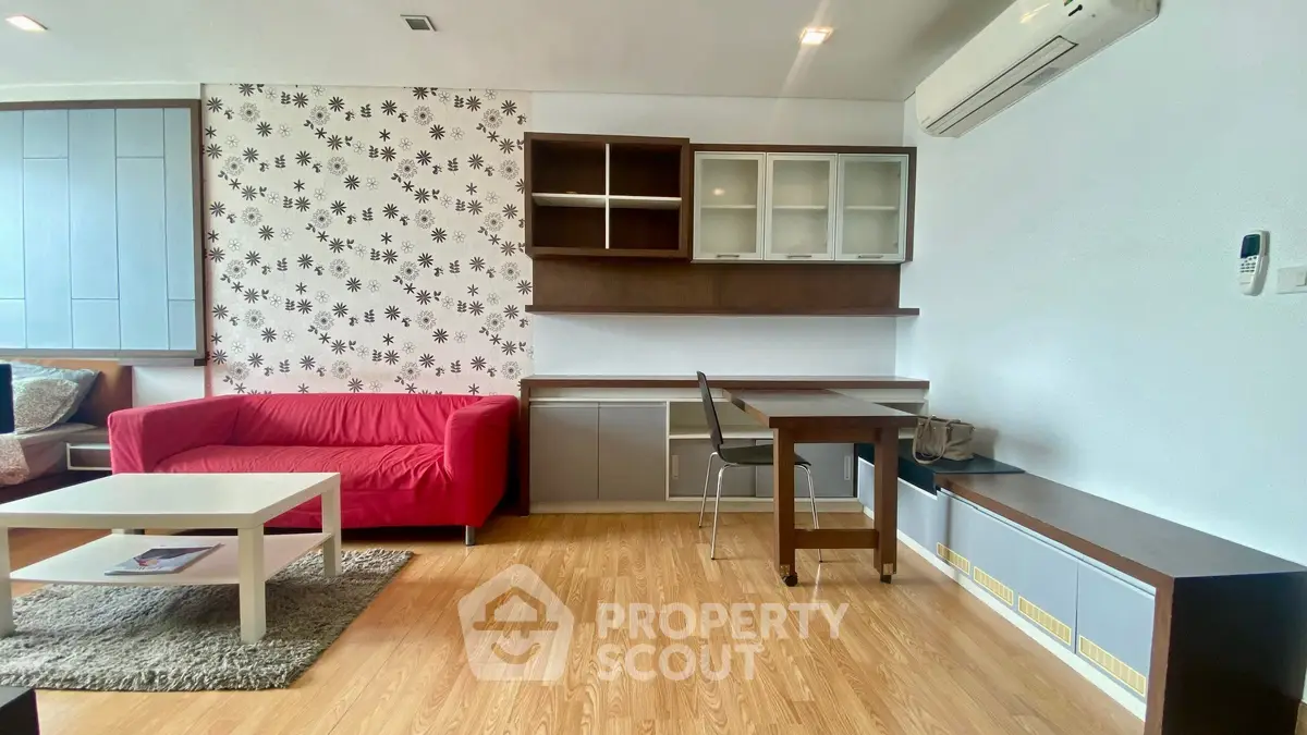 Modern living room with red sofa, wooden flooring, and stylish shelving.