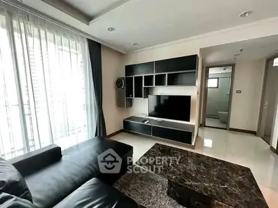 Modern living room with sleek black furniture and large TV unit, perfect for relaxation.