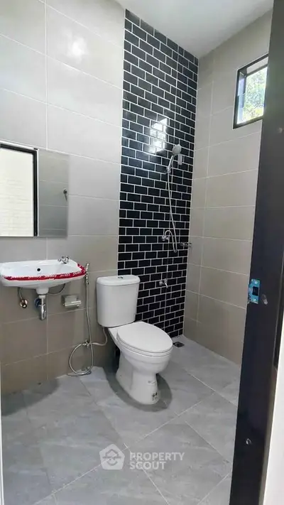 Modern bathroom with sleek black tile accent wall and contemporary fixtures.