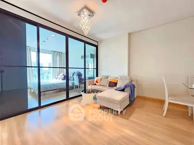 Modern living room with glass partition and elegant chandelier in a stylish apartment.