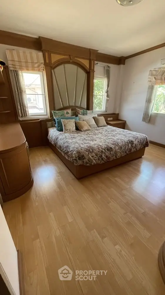 Spacious bedroom with elegant wooden decor and large windows for natural light.