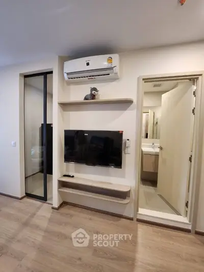 Modern living room with sleek TV setup and adjacent bathroom entry