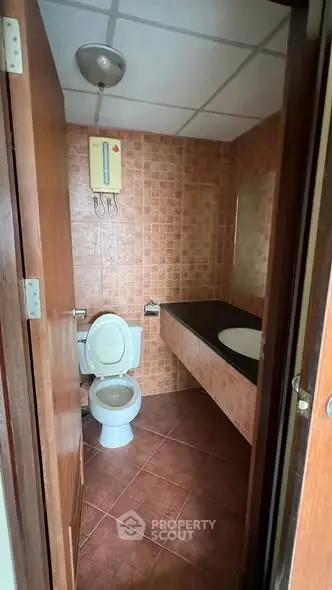 Compact bathroom with tiled walls and modern fixtures in cozy real estate setting.