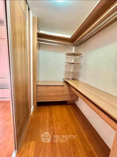 Spacious walk-in closet with wooden shelves and flooring, perfect for organized storage.