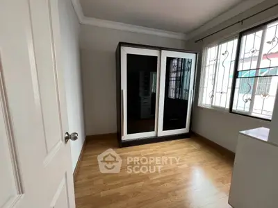 Spacious bedroom with mirrored wardrobe and wooden flooring