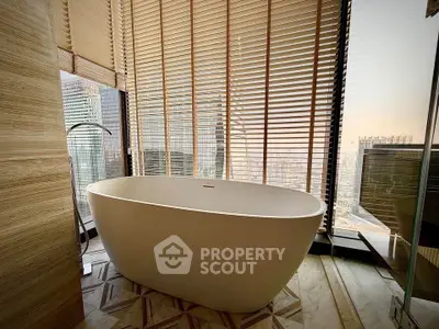 Luxurious bathroom with freestanding bathtub and city view through large windows.
