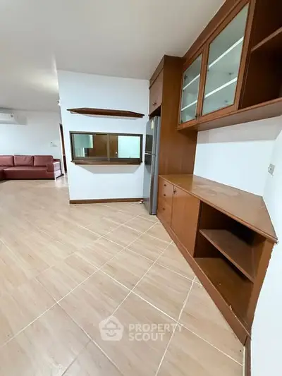 Spacious living room with built-in wooden cabinets and tiled flooring, perfect for modern living.