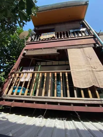 Charming multi-story wooden house with rustic balcony and natural surroundings.