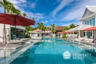 Luxurious tropical villa with stunning pool and palm trees under clear blue sky.