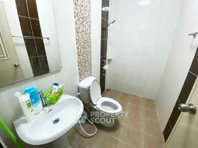 Modern bathroom with sleek fixtures and tiled walls, featuring a toilet, sink, and shower area.