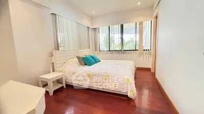 Bright and cozy bedroom with large windows and wooden flooring.