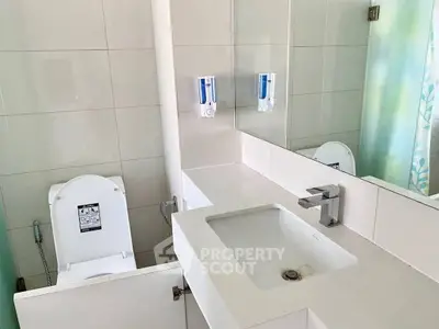 Modern bathroom with sleek sink and toilet, featuring clean lines and neutral tones.