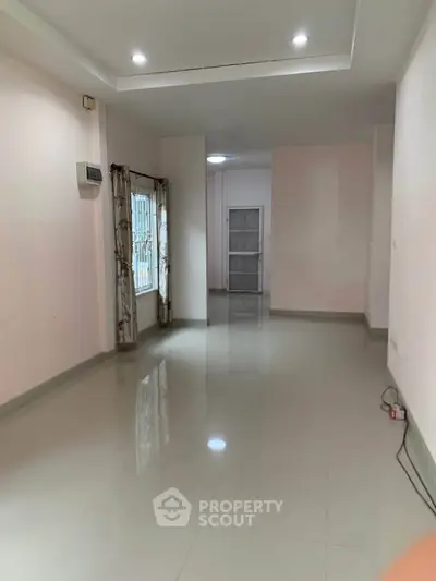 Spacious empty room with glossy tiled floors and natural light, ideal for customization.