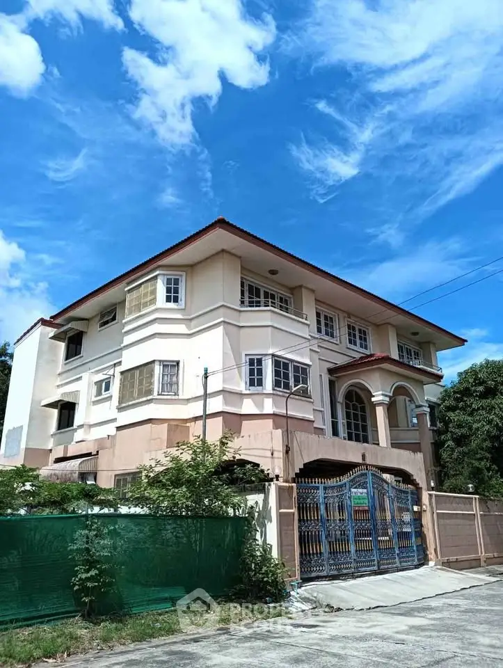 Stunning three-story residential building with elegant facade and gated entrance under clear blue sky.
