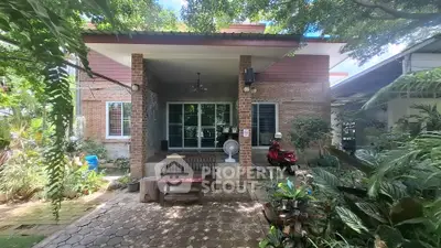 Charming brick house with lush garden and cozy outdoor seating area.