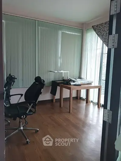 Spacious home office with wooden flooring and large windows for natural light.