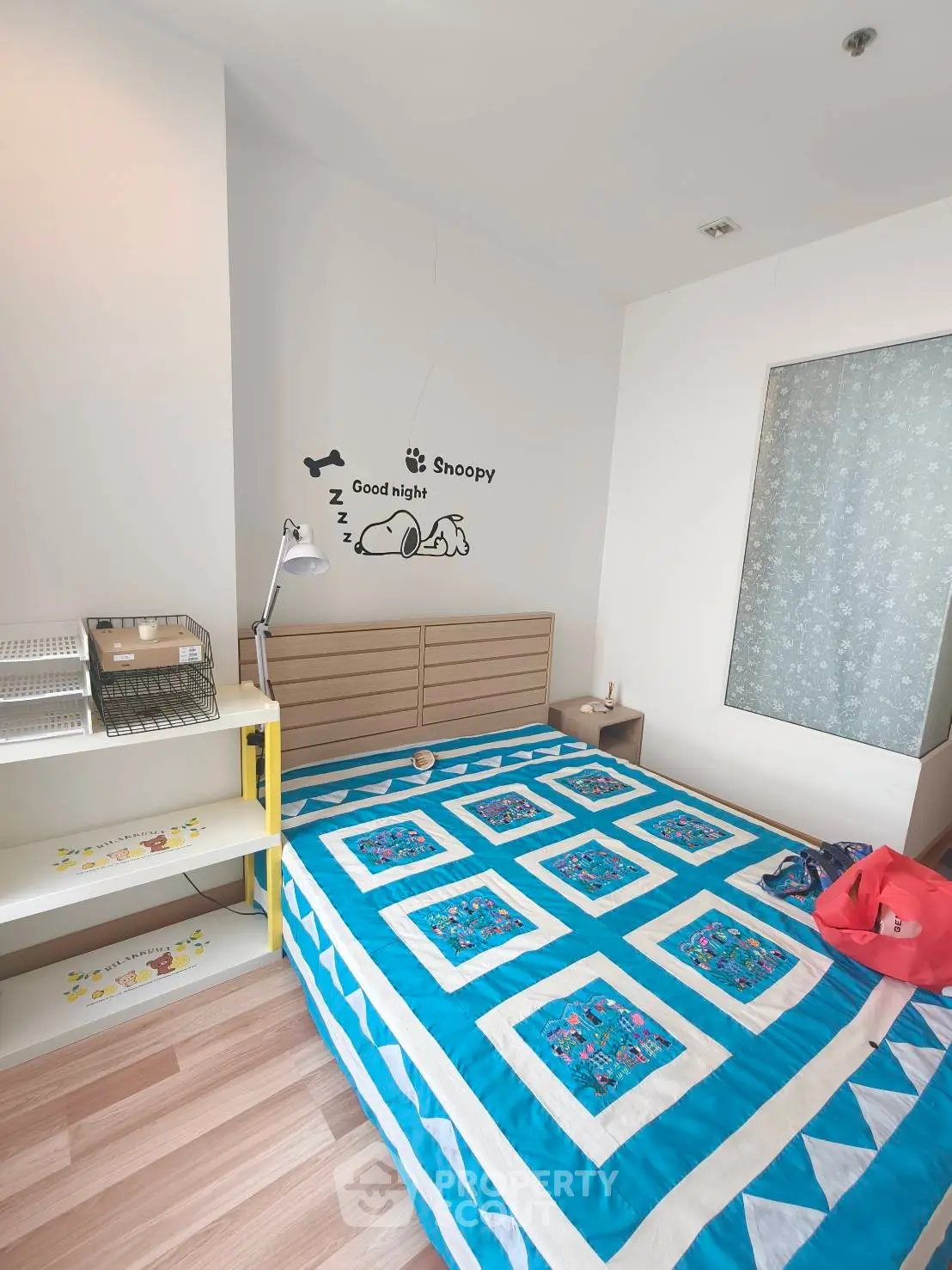 Cozy bedroom with vibrant blue quilt and modern decor, perfect for a restful night's sleep.