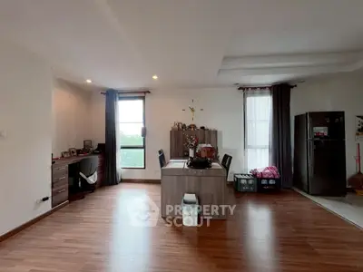 Spacious living room with modern decor and wooden flooring, featuring a dining area and natural light.