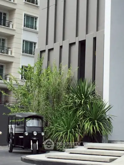 Modern building exterior with lush greenery and unique vehicle parked outside.