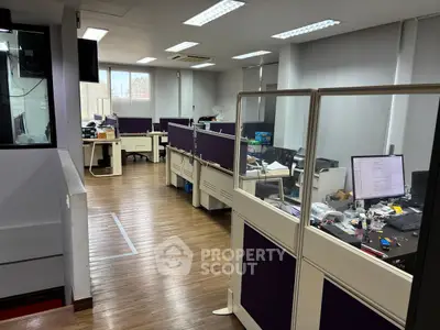 Modern office space with wooden flooring and partitioned workstations