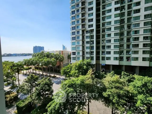 Stunning high-rise building with lush greenery and river view, perfect for urban living.