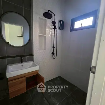 Modern bathroom with sleek fixtures and stylish tile design, featuring a round mirror and contemporary shower setup.
