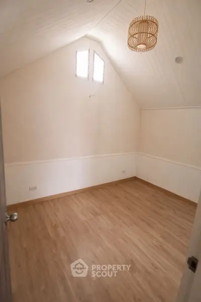 Spacious attic room with wooden flooring and natural light, perfect for a cozy retreat or creative space.