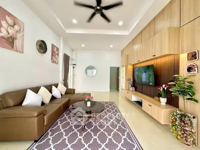 Spacious living room with modern decor and ceiling fan, featuring a cozy brown sofa and stylish entertainment unit.