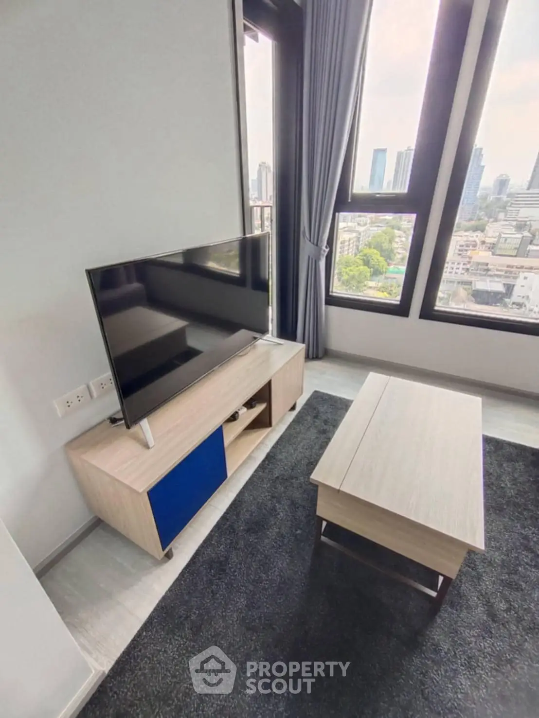 Modern living room with city view, stylish TV stand, and sleek coffee table.