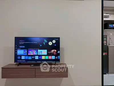 Modern living room with wall-mounted TV and sleek wooden console, showcasing a minimalist design.