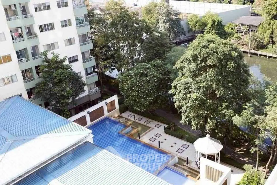 Stunning aerial view of a modern apartment complex with a luxurious pool and lush greenery.