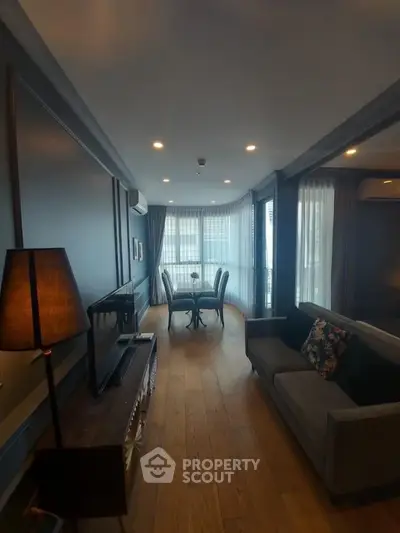Elegant living room with modern decor and wooden flooring, featuring a cozy seating area and stylish lighting.