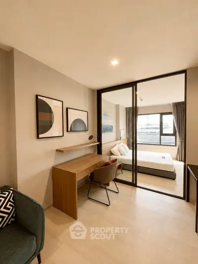 Modern bedroom with stylish decor and workspace, featuring large windows and natural light.
