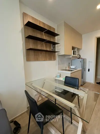 Modern kitchen with glass dining table and sleek shelving in a stylish apartment.