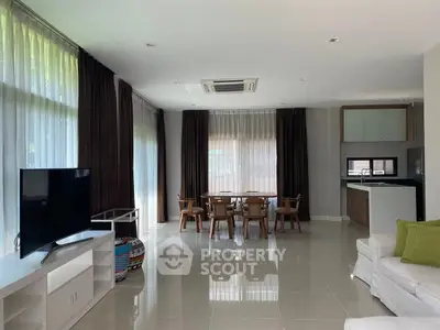 Spacious modern living room with dining area and sleek kitchen, featuring large windows and stylish decor.