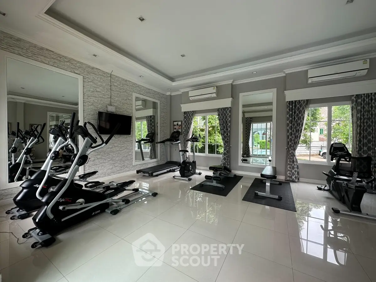 Spacious home gym with modern exercise equipment and large windows for natural light.