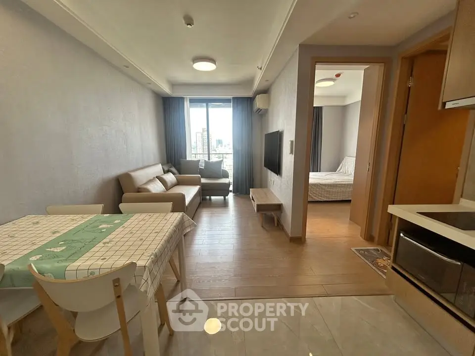 Modern apartment interior with open living room and dining area, featuring stylish furniture and natural light.