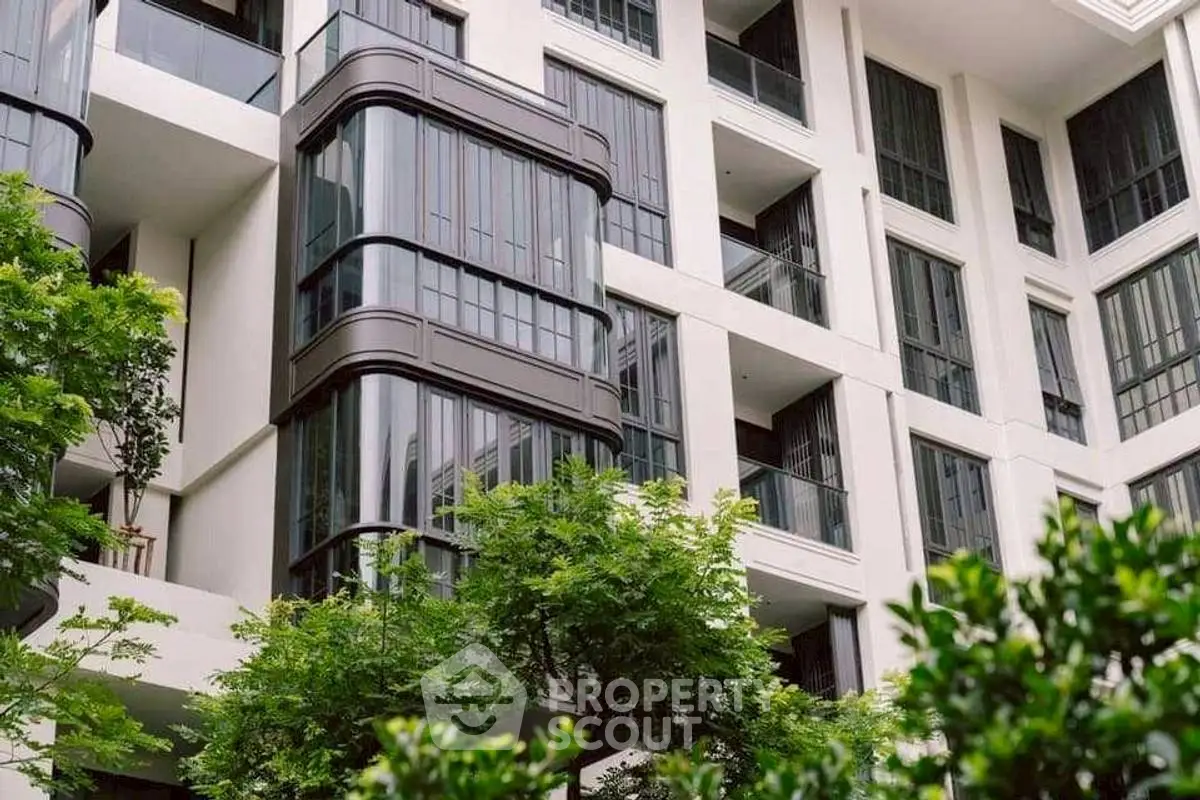 Modern apartment building with sleek glass balconies and lush greenery