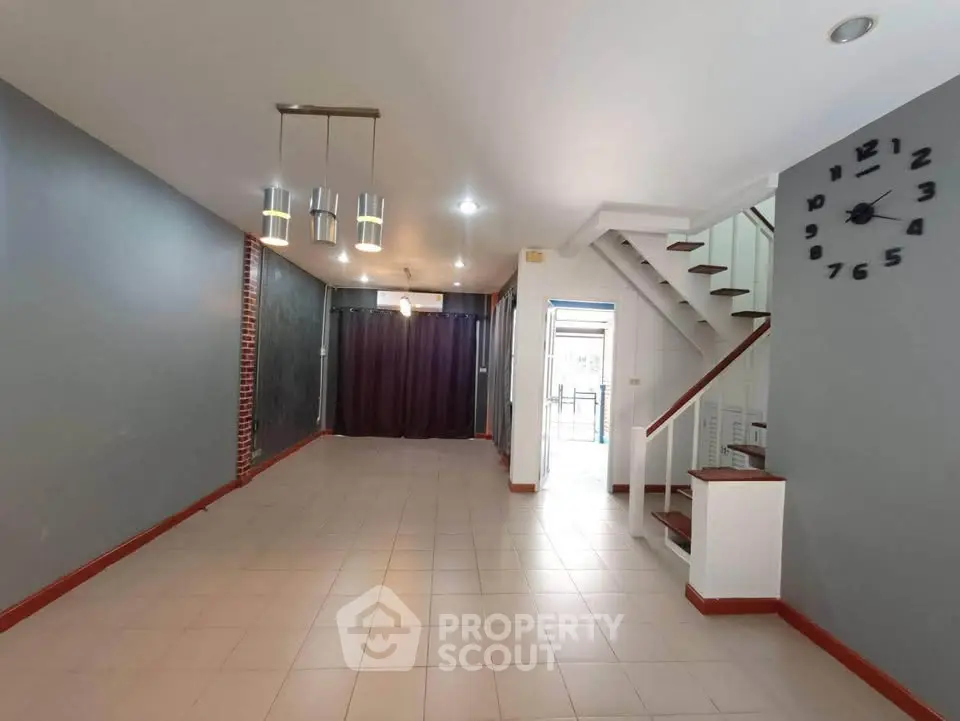 Spacious open-plan living area with modern lighting and staircase, perfect for family gatherings.