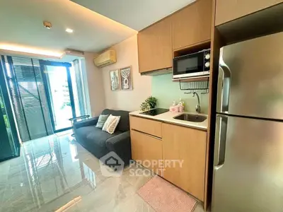 Modern apartment with sleek kitchen and cozy living area, featuring large windows and stylish decor.