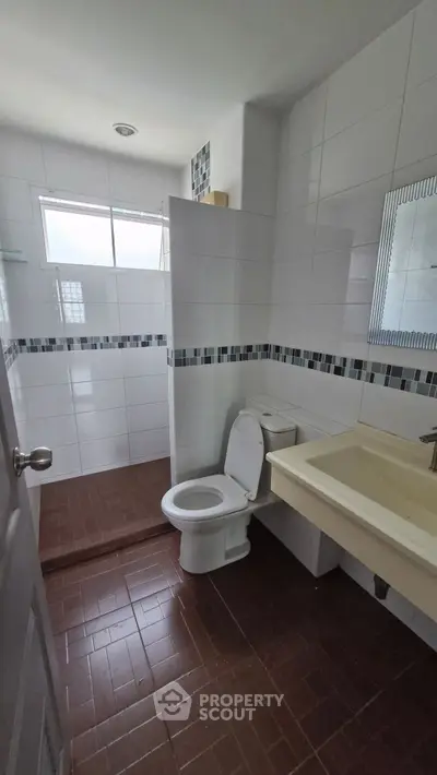 Modern bathroom with tiled walls and floor, featuring a toilet and sink.