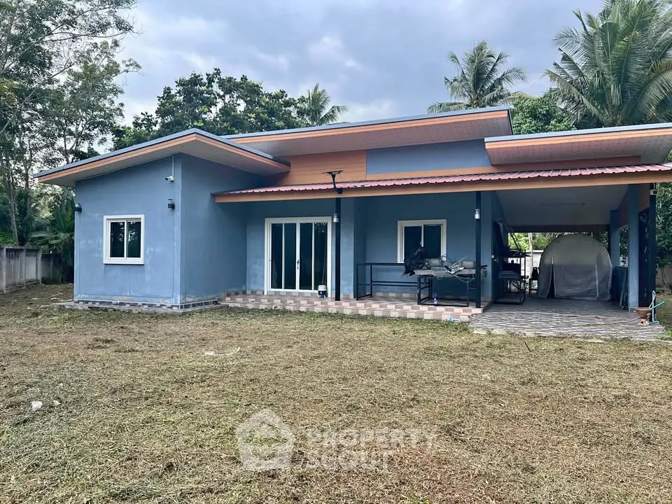 Charming single-story blue house with spacious yard and modern design, perfect for family living.