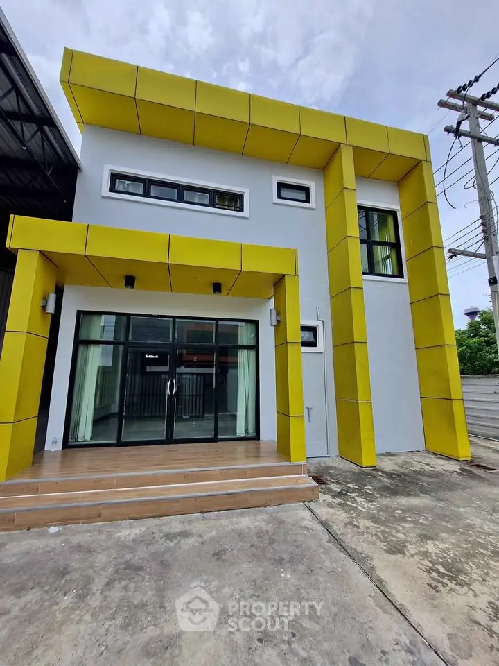 Modern yellow-accented building exterior with large glass doors and minimalist design.