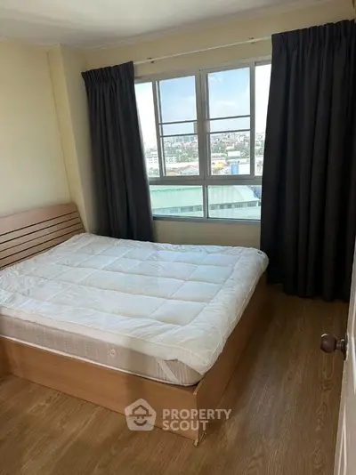 Cozy bedroom with large window offering city views, featuring a comfortable bed and elegant wooden flooring.