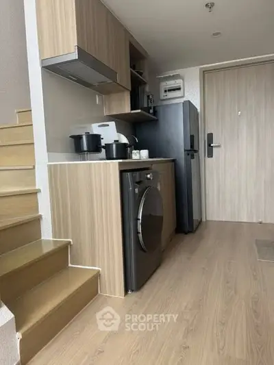 Modern compact kitchen with washing machine and fridge in stylish apartment